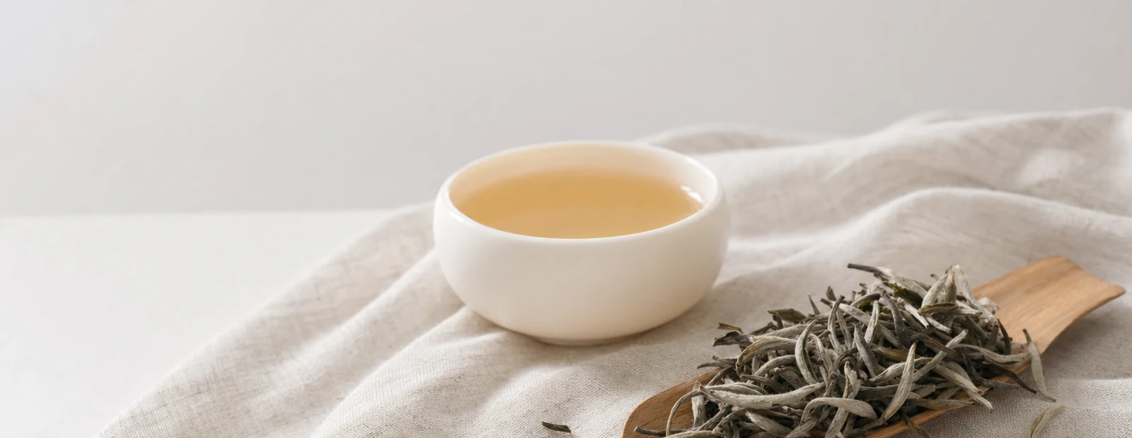 Realistic white tea hero photograph with downy tea buds, pale liquor, and teaware.